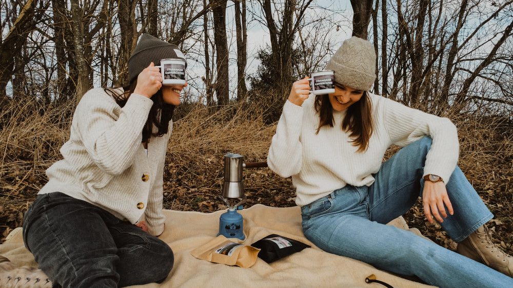 2 Frauen mit Kaffeetasse in der Hand auf einer Picknickdecke